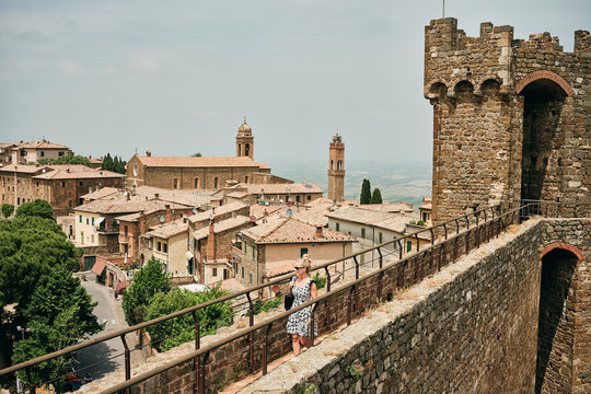 Woman walking on stony wall with observation tower and looking at town