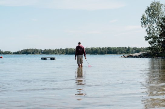 man standing in the water with a fishing net in summer