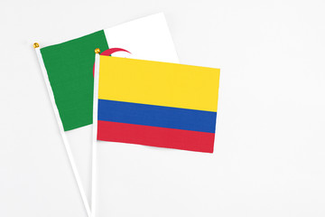 Colombia and Algeria stick flags on white background. High quality fabric, miniature national flag. Peaceful global concept.White floor for copy space.