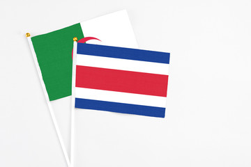 Costa Rica and Algeria stick flags on white background. High quality fabric, miniature national flag. Peaceful global concept.White floor for copy space.