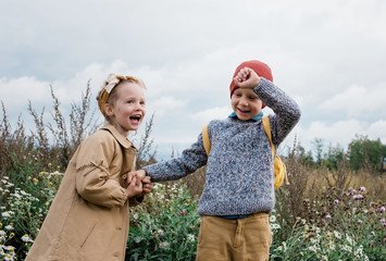 brother and sister holding hands laughing and playing outside