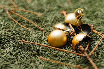 Broken golden Christmas balls on fallen dry Christmas tree needles with branches.