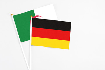 Germany and Algeria stick flags on white background. High quality fabric, miniature national flag. Peaceful global concept.White floor for copy space.