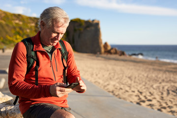 Senior man using smart phone while standing at beach