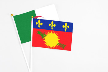Guadeloupe and Algeria stick flags on white background. High quality fabric, miniature national flag. Peaceful global concept.White floor for copy space.