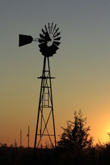 silhouette of windmill at sunset on a Kansas farm out in the country.