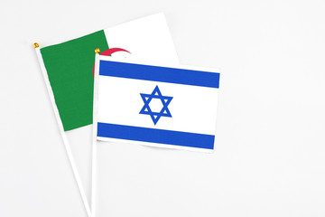 Israel and Algeria stick flags on white background. High quality fabric, miniature national flag. Peaceful global concept.White floor for copy space.