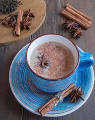 cup of masala tea with cinnamon and star anise in a blue mug on  a wood background 