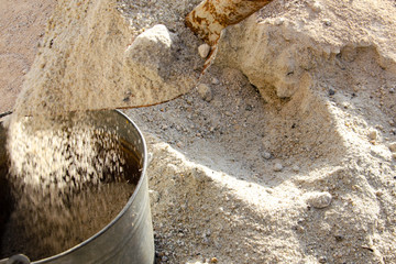 Loading sand with a shovel into a bucket