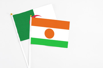 Niger and Algeria stick flags on white background. High quality fabric, miniature national flag. Peaceful global concept.White floor for copy space.