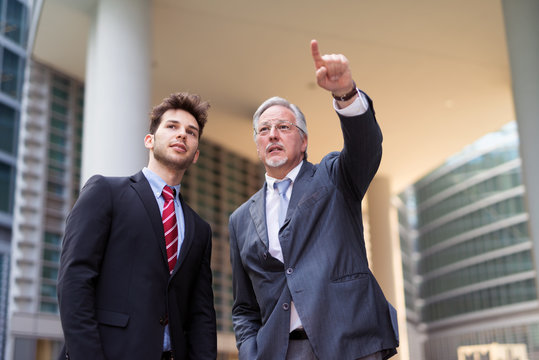 Senior businessman indicating the right direction to the younger one