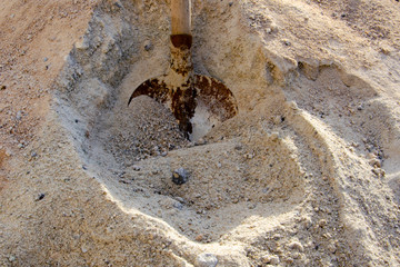 Loading sand with a shovel into a bucket