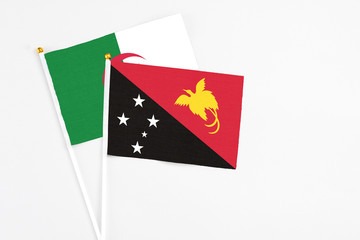 Papua New Guinea and Algeria stick flags on white background. High quality fabric, miniature national flag. Peaceful global concept.White floor for copy space.