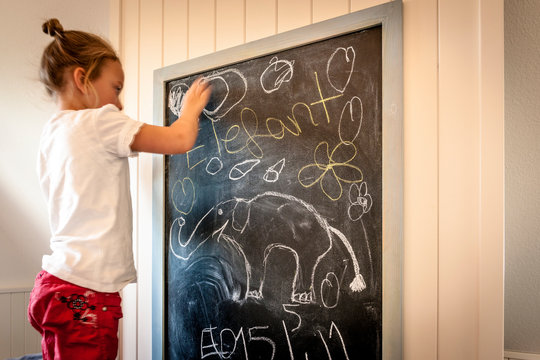 Little girl drawing on blackboard