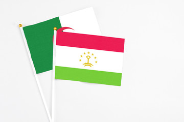 Tajikistan and Algeria stick flags on white background. High quality fabric, miniature national flag. Peaceful global concept.White floor for copy space.