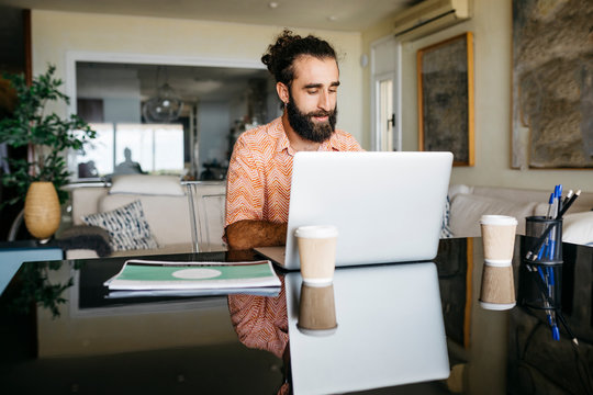 Man working on table at home using laptop