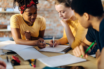 Young people sitting together at table and taking notes