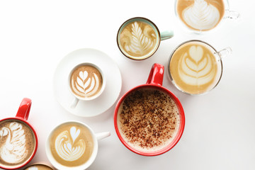 Buch of coffee cups with different kind of beverage and different latte art foam designs. Top view, close up, copy space, background.