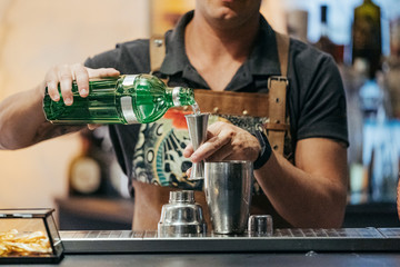 Bartender mixing cocktail in a bar, using jigger