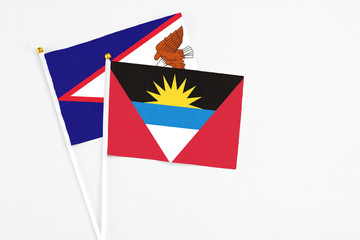 Antigua and Barbuda and American Samoa stick flags on white background. High quality fabric, miniature national flag. Peaceful global concept.White floor for copy space.