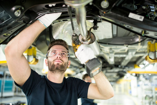 Man working at car underbody in modern factory