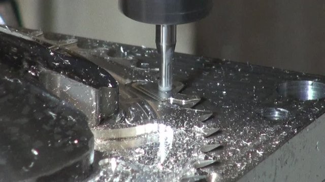 Zoom of a small cylindrical sander notching a metal disk with pinions, jumping from one part to another of it, from a metal industry where different types of pieces are manufactured.