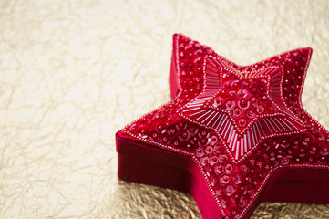 Ornate star-shaped burgundy gift box on a festive metallic gold background of copy space