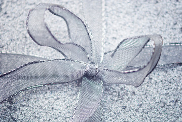 Festive silver mesh bow in full frame close-up on textured metallic gift box background