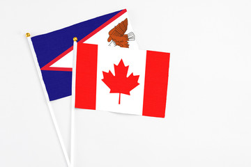 Canada and American Samoa stick flags on white background. High quality fabric, miniature national flag. Peaceful global concept.White floor for copy space.