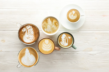 Buch of coffee cups with different kind of beverage and different latte art foam designs. Top view, close up, copy space, background.
