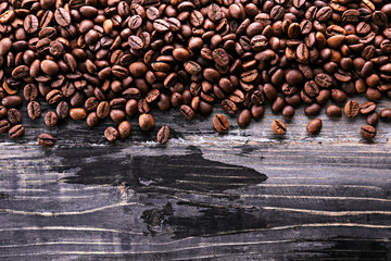 Roasted brown coffee beans scattered on wood textured table with a lot copy space for text. Flat lay composition. Close up, top view, background.