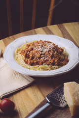 Pasta bolognese (spaghetti bolognese) and parmesan on a white plate. The classic italian spaghetti on old wooden background