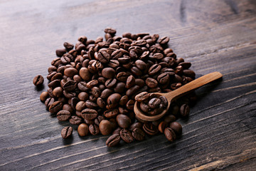 Roasted brown coffee beans scattered on wood textured table with a lot copy space for text. Flat lay composition. Close up, top view, background.