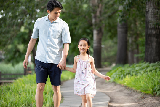 Happy Chinese father and daughter walking in park