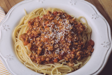 Pasta bolognese (spaghetti bolognese) and parmesan on a white plate. The classic italian spaghetti on old wooden background