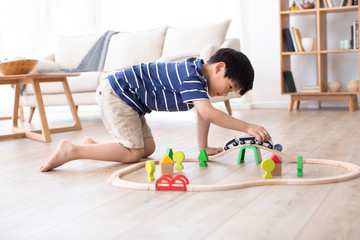 Little Chinese boy playing with toy train on floor