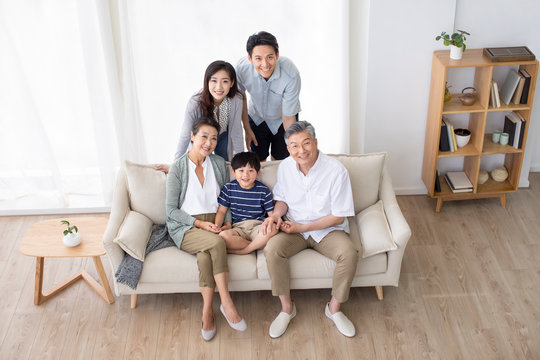 Happy Chinese Family Relaxing On Sofa