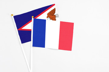 France and American Samoa stick flags on white background. High quality fabric, miniature national flag. Peaceful global concept.White floor for copy space.