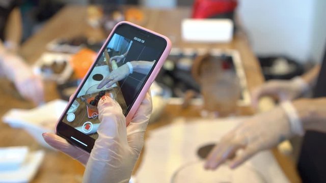 Woman shoots a video of a culinary master class on a smartphone