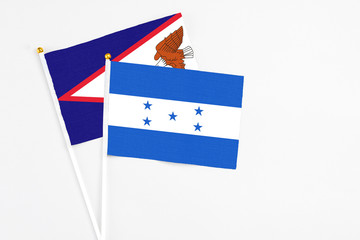Honduras and American Samoa stick flags on white background. High quality fabric, miniature national flag. Peaceful global concept.White floor for copy space.