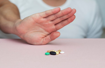 man refuses pills, pills on the table, health, medicine, pink background