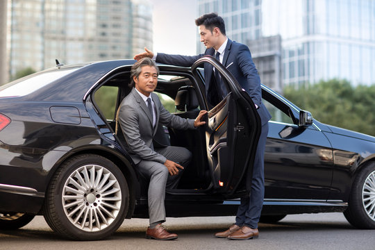 Confident Chinese businessman getting out of car