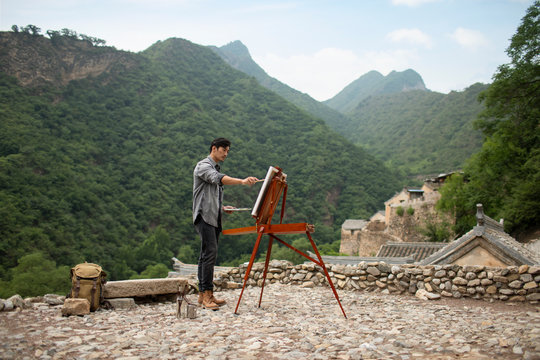 Young Chinese man painting outdoors