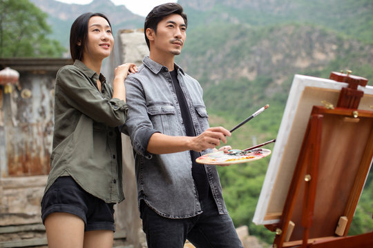 Young Chinese couple painting outdoors