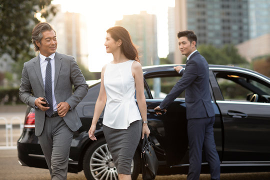 Confident Chinese business people getting out of car