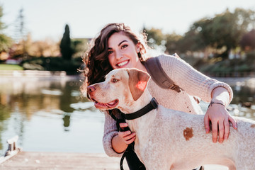young woman and her dog outdoors in a park with a lake. sunny day, autumn season