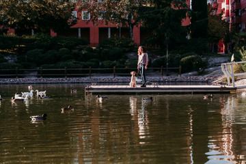 Fototapeta na wymiar young woman and her dog outdoors in a park with a lake. sunny day, autumn season