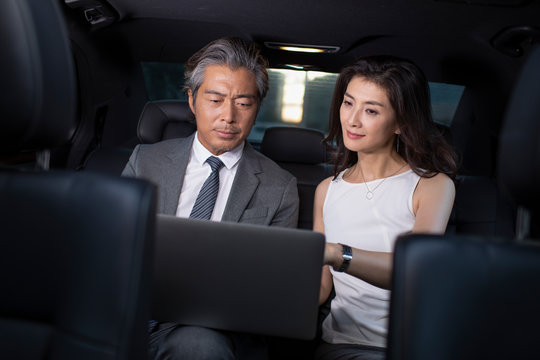Successful Chinese business people using laptop in a car