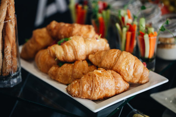 lots of fresh croissants on a white plate on the buffet in the restaurant