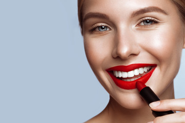 Beautiful girl with red lips and classic makeup with lipstick in hand. Beauty face